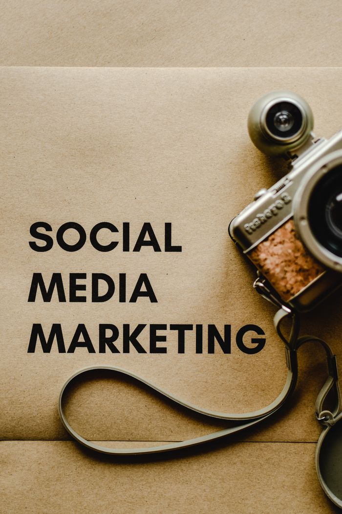 hero-img-01 Close-up of a vintage camera next to a social media marketing concept text on a brown background.